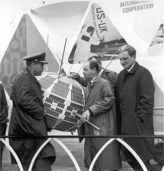 April 20, 1964 - NASA Public Affairs Officer "Shorty" Powers with unidentified officials in front of Allouette satellite mock-up. Shorty Powers was the "voice of Project Mercury."